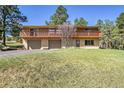 Two-story home with brick facade, a two-car garage, upper deck with wood railing, and mature trees at 29551 Dorothy Rd, Evergreen, CO 80439