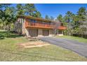Two-story home features a brick facade, a two-car garage, and a large upper deck with a wood railing at 29551 Dorothy Rd, Evergreen, CO 80439