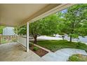 Covered front porch with white railings, offering a serene view of the landscaped yard and mature trees at 6364 S Walden Ct, Aurora, CO 80016