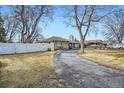 Residential home featuring a traditional brick exterior with a white fence and mature trees at 4585 Garrison St, Wheat Ridge, CO 80033