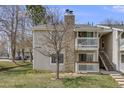Charming condo with a stone chimney, two balconies, a well-kept lawn, and stairs to the upper level at 14192 E Colorado Dr # 102, Aurora, CO 80012