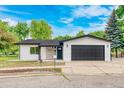 Charming one-story home featuring a stucco exterior, stone accents, and a black attached two-car garage at 6882 Quail St, Arvada, CO 80004