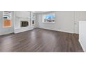 Bright living room featuring a cozy fireplace, hardwood floors, and large windows at 206 River Rd, Platteville, CO 80651
