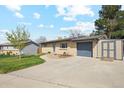 A cozy single-story brick home with a lush green lawn, mature tree and attached garage at 320 Orion St, Golden, CO 80401