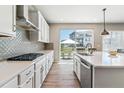 Bright kitchen with stainless steel appliances, white cabinetry, and a large window overlooking the backyard at 7240 S White Crow Way, Aurora, CO 80016
