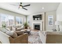 Cozy living room with a fireplace, plush seating, large windows, and ample natural light at 7240 S White Crow Way, Aurora, CO 80016