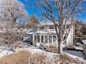 Back exterior featuring an enclosed sunroom with many windows and a well-maintained yard with mature trees at 4667 Ashfield Dr, Boulder, CO 80301