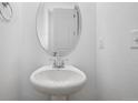 Powder room features a pedestal sink, oval mirror, and neutral walls at 45915 Wood Thrush Ave, Bennett, CO 80102