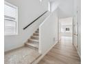 Bright entryway featuring wood floors, neutral walls, carpeted stairs, and a window for natural light at 45915 Wood Thrush Ave, Bennett, CO 80102