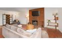 Cozy living room featuring a large grey couch, wood floors, and brick fireplace with mounted TV at 3341 S Monaco Pkwy # A, Denver, CO 80222