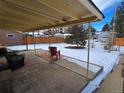 Covered patio with seating area overlooking a snow-covered backyard at 1227 Aspen St, Longmont, CO 80501