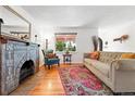 Bright living room boasting a decorative fireplace, hardwood floors, and a large window with green outdoor views at 1332 Ash St, Denver, CO 80220