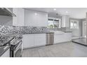 Bright kitchen with white cabinetry, stainless steel appliances, and a farmhouse sink beneath a window at 482 W Caley Ave, Littleton, CO 80120