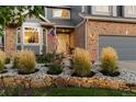 Close-up of the home's front entrance featuring a white door, stone garden bed, and manicured ornamental grasses at 320 Crossing Cir, Castle Pines, CO 80108