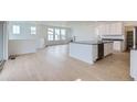 Modern kitchen flows into the open-concept living area, with stainless appliances, an island, and light hardwood floors at 2094 S Haleyville Way, Aurora, CO 80018