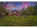 Expansive backyard of this brown home features a large lawn and patio with outdoor seating at 8576 Niwot Meadow Farm Rd, Niwot, CO 80503
