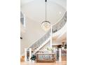 Grand foyer showcasing a curved staircase, wrought iron railings, designer chandelier, and sun-filled interiors at 175 S Jasmine St, Denver, CO 80224