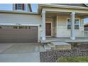 House exterior featuring a front porch, attached garage, and landscaping at 17326 E 91 Way, Commerce City, CO 80022