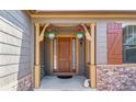 Inviting entryway with hanging flower baskets, decorative stone accents, and a charming covered porch at 25402 E Glasgow Pl, Aurora, CO 80016