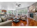 Open-concept living room with stone fireplace, hardwood floors, and access to the kitchen and dining area at 25402 E Glasgow Pl, Aurora, CO 80016