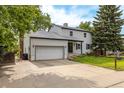Charming two-story home with a well-maintained lawn and an attached garage with long driveway at 7431 Webster St, Arvada, CO 80003
