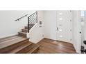 Bright entryway features sleek hardwood floors, modern staircase with black metal railing, and a door with window panes at 1255 Penner Dr, Erie, CO 80026