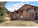 Inviting condo exterior featuring wood siding, dual staircase entries, and manicured lawn at 9077 W 88Th Cir, Denver, CO 80021