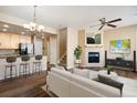 Inviting living room featuring a fireplace, ceiling fan, and an open layout flowing into the kitchen at 16149 E Geddes Ln # 99, Aurora, CO 80016