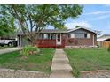 Inviting home featuring a red porch and gray siding, complimented by a well-manicured lawn and a mature tree at 1263 W 103Rd Pl, Northglenn, CO 80260