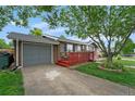 Charming home with a front-facing garage and a red porch, surrounded by a green lawn and mature trees at 1263 W 103Rd Pl, Northglenn, CO 80260