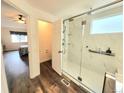 Modern bathroom with glass shower, marble-look tile, wood floors, and view into the bedroom at 21924 E Lake Ave, Aurora, CO 80015