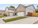 Side view of house with three-car garage, stone landscaping, and manicured lawn at 4545 Oxbow Dr, Brighton, CO 80601