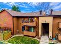 Exterior view of a two-story townhome with dual balconies, brick accents and a well-maintained lawn at 7080 W 20Th Ave # 202, Lakewood, CO 80214