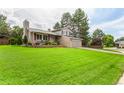 A well-maintained two story home featuring a lush green lawn and mature trees in a suburban setting at 8588 S Woody Way, Highlands Ranch, CO 80126