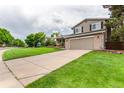 View of home showing the driveway, front lawn, and neutral exterior paint at 8588 S Woody Way, Highlands Ranch, CO 80126
