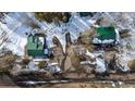An aerial view of a property featuring a house and a garage with green metal roofs nestled among trees at 9061 N Rex Ln, Conifer, CO 80433