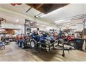 Spacious garage interior filled with vehicles, tools, and a trailer under bright lighting at 9061 N Rex Ln, Conifer, CO 80433