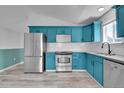 Spacious kitchen with blue cabinets, stainless steel appliances, and light gray wood-look flooring at 3470 W Walsh Pl, Denver, CO 80219