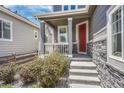 Inviting front porch with a red door, stone accents, and cozy seating area at 10887 Endeavor Dr, Parker, CO 80134
