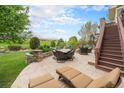 Spacious stamped concrete patio with outdoor seating, a fire pit, and lush landscaping overlooking the golf course at 2349 Hickory Pl, Erie, CO 80516