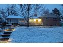 Charming home at dusk with snow-covered yard and illuminated pathway to front door at 11845 W 30Th Pl, Lakewood, CO 80215