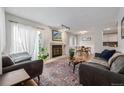 Bright living room featuring two couches, a fireplace, large windows with sheer curtains, and hardwood floors at 10290 W Jewell Ave # B, Lakewood, CO 80232