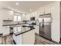 Modern kitchen boasts white cabinets, stainless steel appliances, and a center island at 655 S Osceola St, Denver, CO 80219