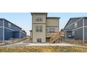 Backyard of the two-story home with a walkout patio, wooden staircase, and xeriscaping at 140 Racer St, Bennett, CO 80102