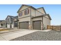 A charming two-story home showing a three-car garage and complemented by stone-accented columns at 140 Racer St, Bennett, CO 80102