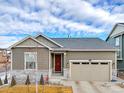 Inviting home with a red door, light stone accents, and a well-maintained front yard at 9694 Truckee St, Commerce City, CO 80022