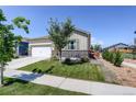 Well maintained front yard with mature tree and view of two-car garage at 8861 Ventura St, Commerce City, CO 80022