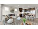 Open-concept living space with an electric fireplace, gray accent chairs, and dark wood kitchen at 46550 Avery Ln, Bennett, CO 80102