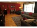 Comfortable living room showcasing hardwood floors, a red accent wall, and ample natural light at 1936 S Poplar St, Denver, CO 80224