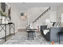 Cozy living room featuring a comfortable gray sofa, textured rug, and staircase at 7700 W Glasgow Pl # 10A, Littleton, CO 80128